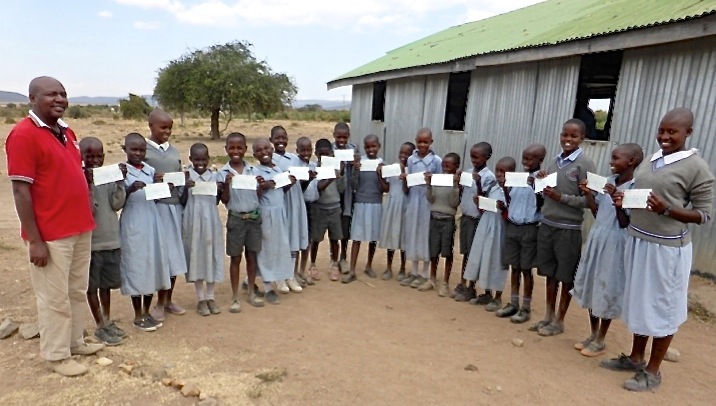 Daniel Njaga presents cheques to pupils of Tumaini School